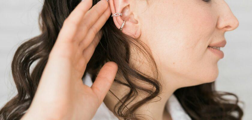 Cropped close-up shot of a young woman with asymmetrical silver ear cuffs. Female with metal ear