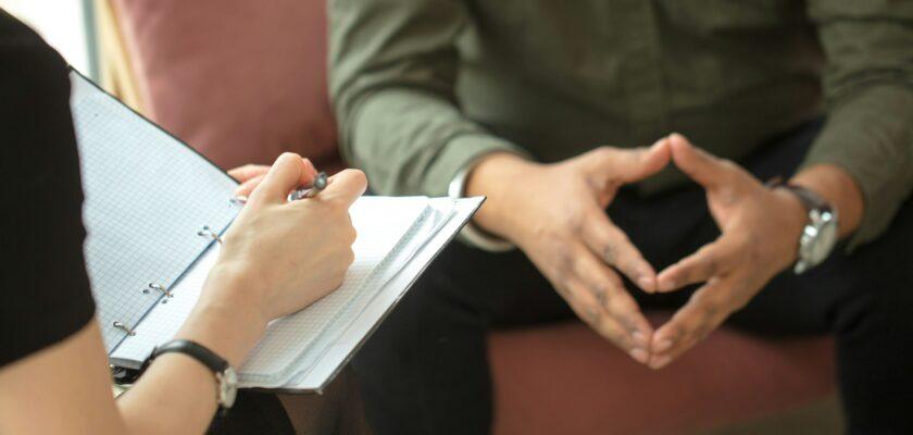 psychologist consulting indian man, writing notes during psychological therapy session