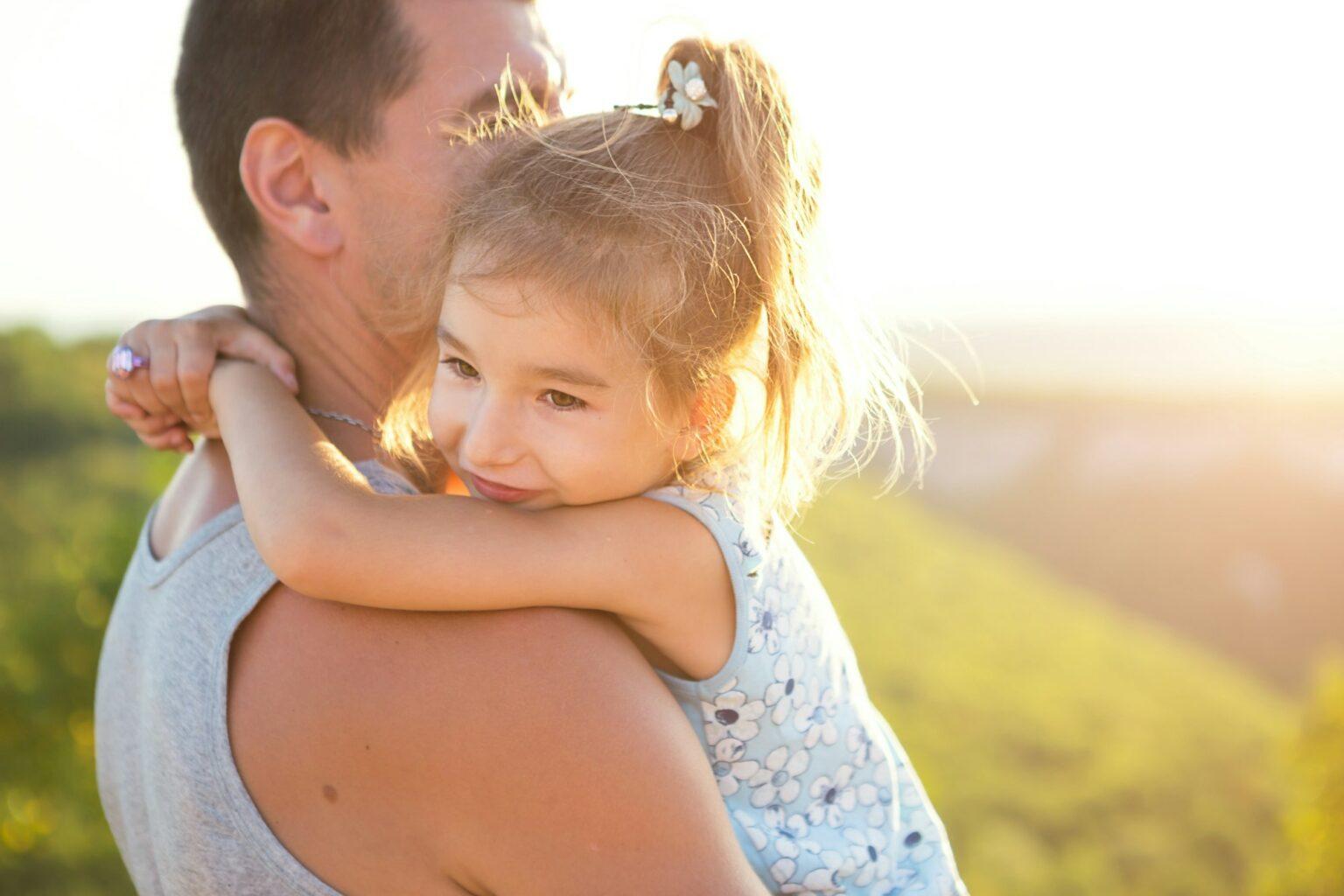 The father and daughter hug tightly, the girl holds the father by the neck,