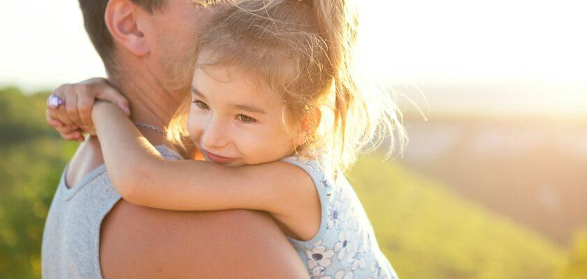 The father and daughter hug tightly, the girl holds the father by the neck,