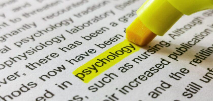 Close-up image of marker highlighting word psychology in book.