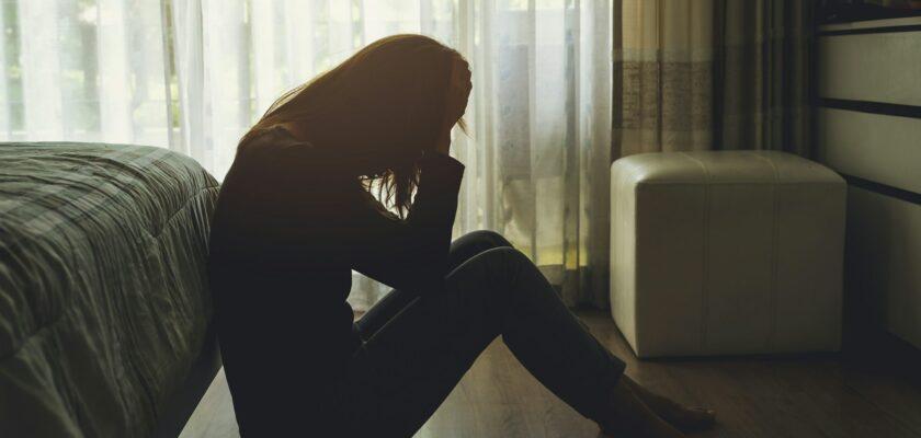 depressed woman sitting in the dark bedroom