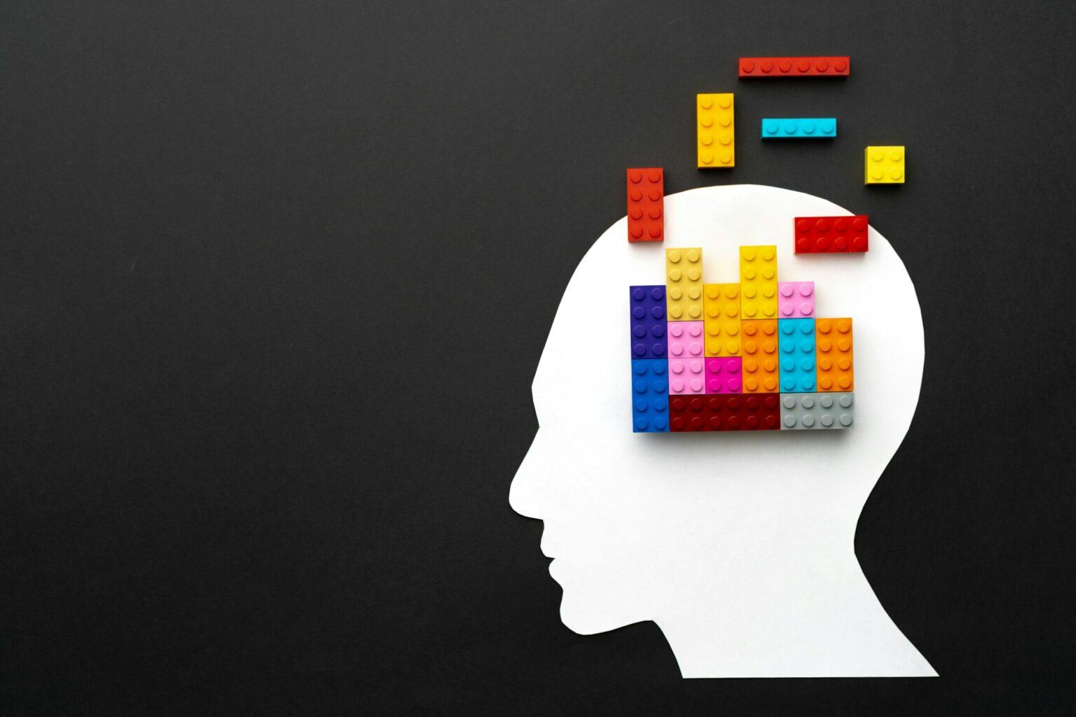 L’influence durable de Jean Piaget : pionnier de la psychologie du développement cognitif Papercut silhouette of human head with colorful constructor pieces