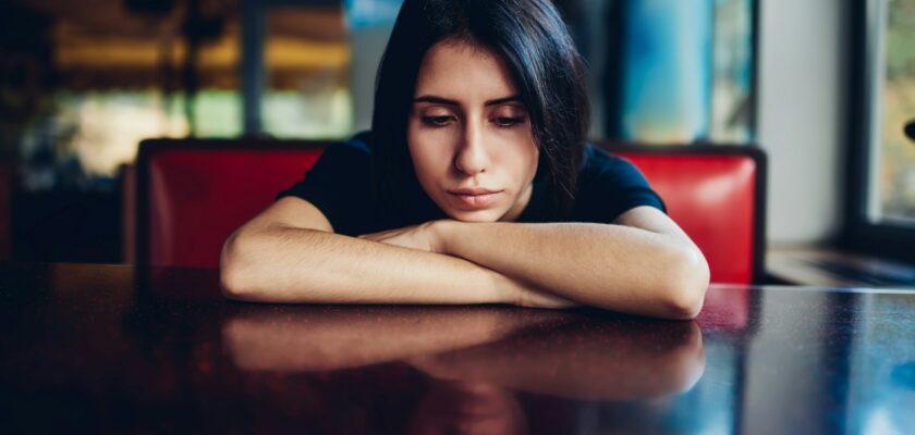 Sad woman leaning on table in cafe