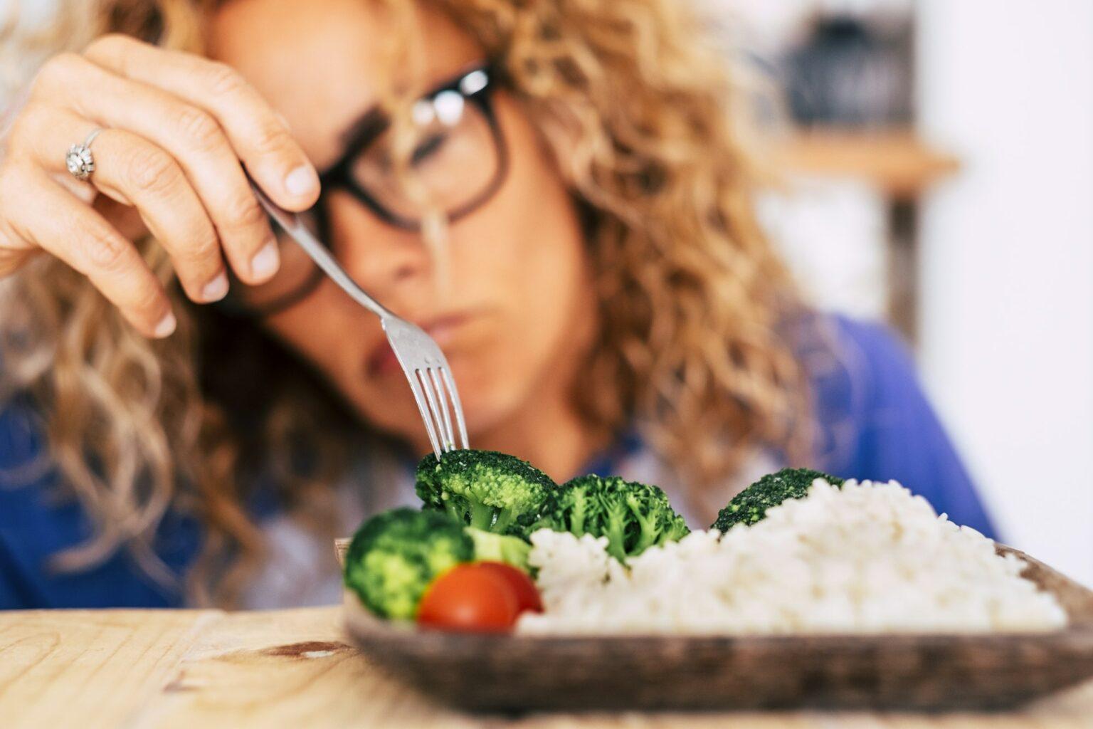 woman looking with disgust at some vegetables and rise on the table