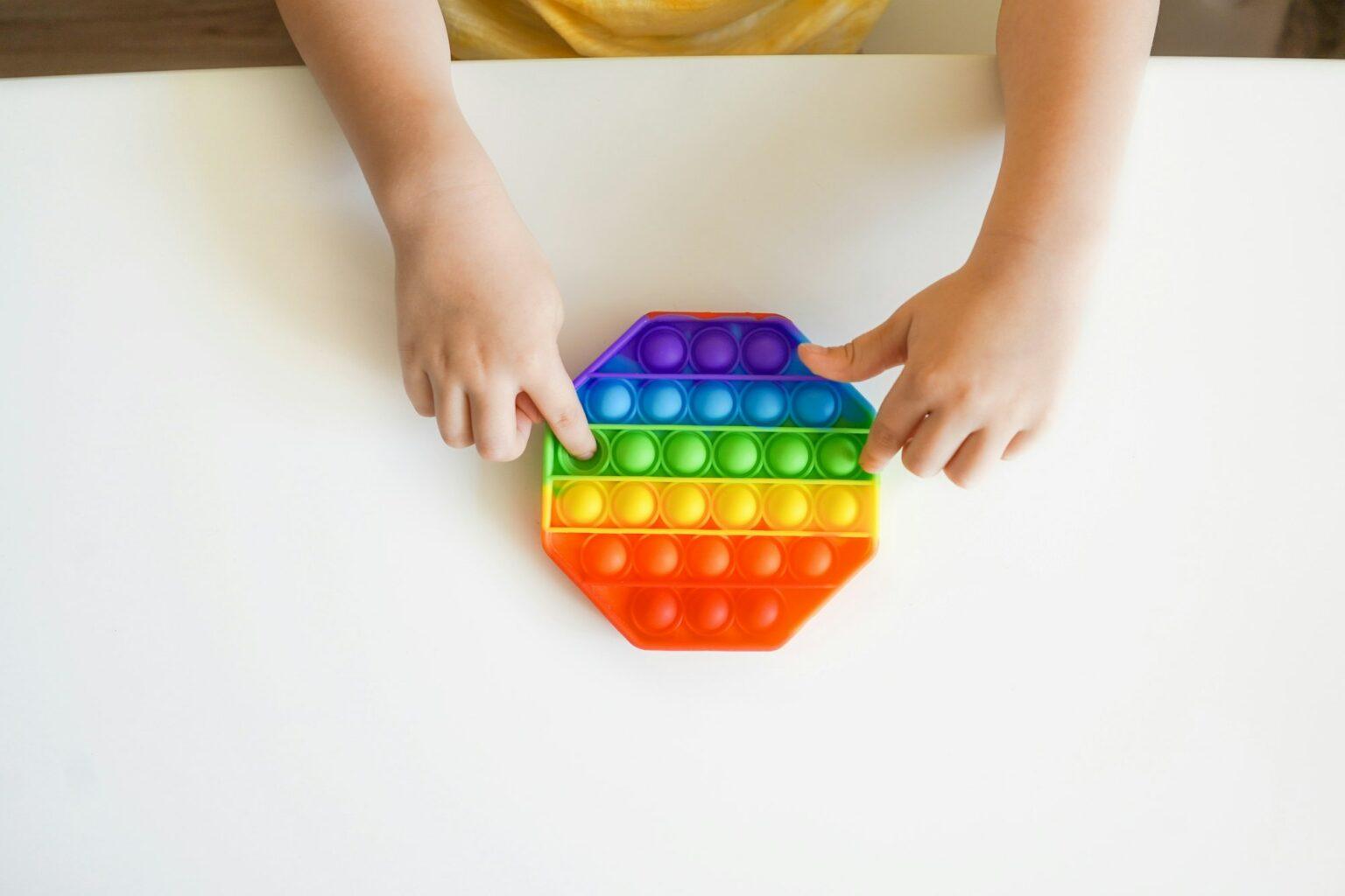 La coordination œil-main des enfants : un lien crucial avec leurs performances académiques Colorful Pop it fidget in kid's hands.