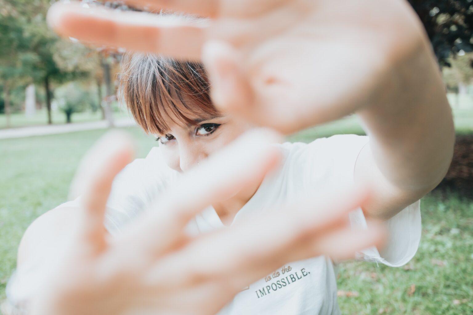 Manque de confiance en soi : comprendre, surmonter et s’épanouir Young woman covering the lens with his hands while smiling to camera shy. Shyness