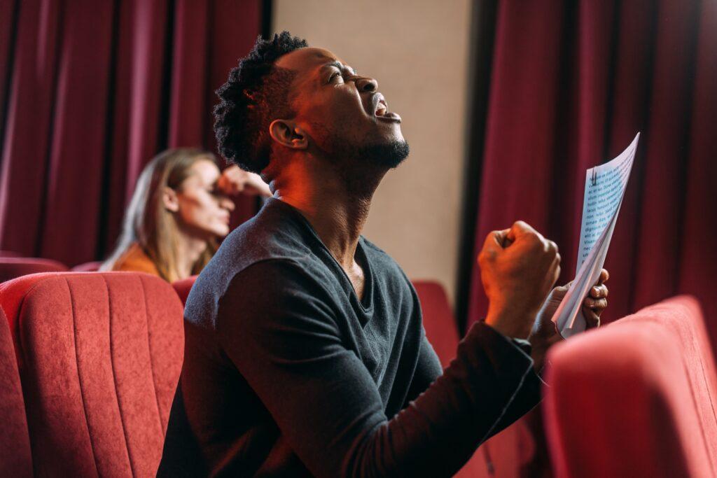 african american sad actor shouting and rehearsing in theatre with young actor