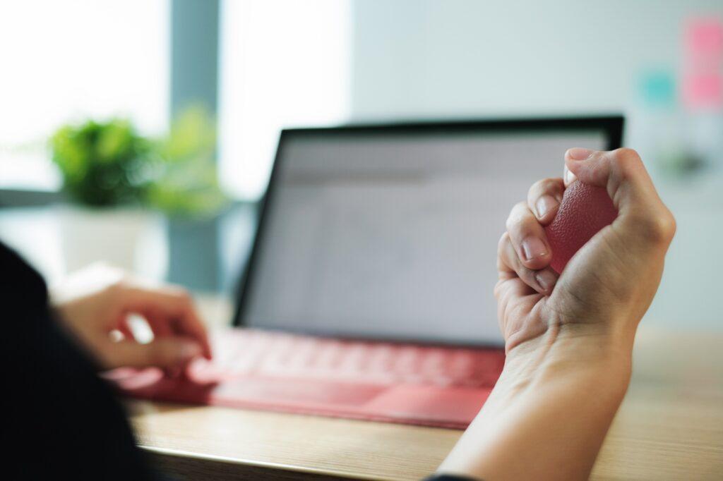 Close-up of anxious woman hands holding antistress ball at work.