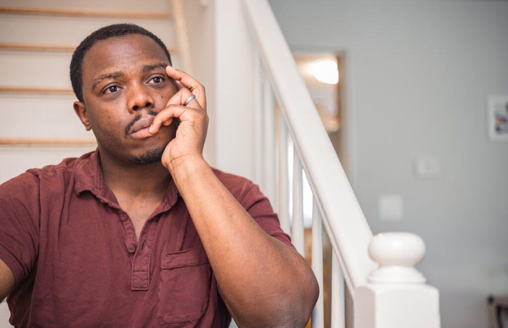 Depressed and anxious African American or black man sitting at home