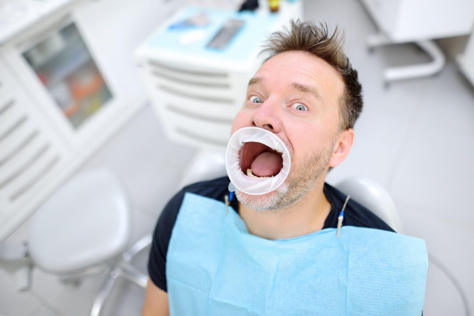Frightened patient in the chair on dental clinic. Orthodontist and prosthetics appointment.