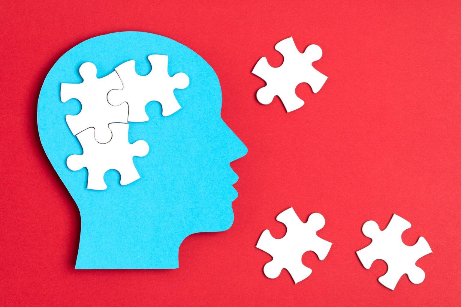 Papercut head with jigsaw puzzle pieces inside. Mental health problems, psychology, memory, logic