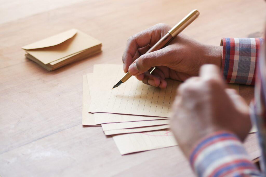 rear view of man writing letter on table