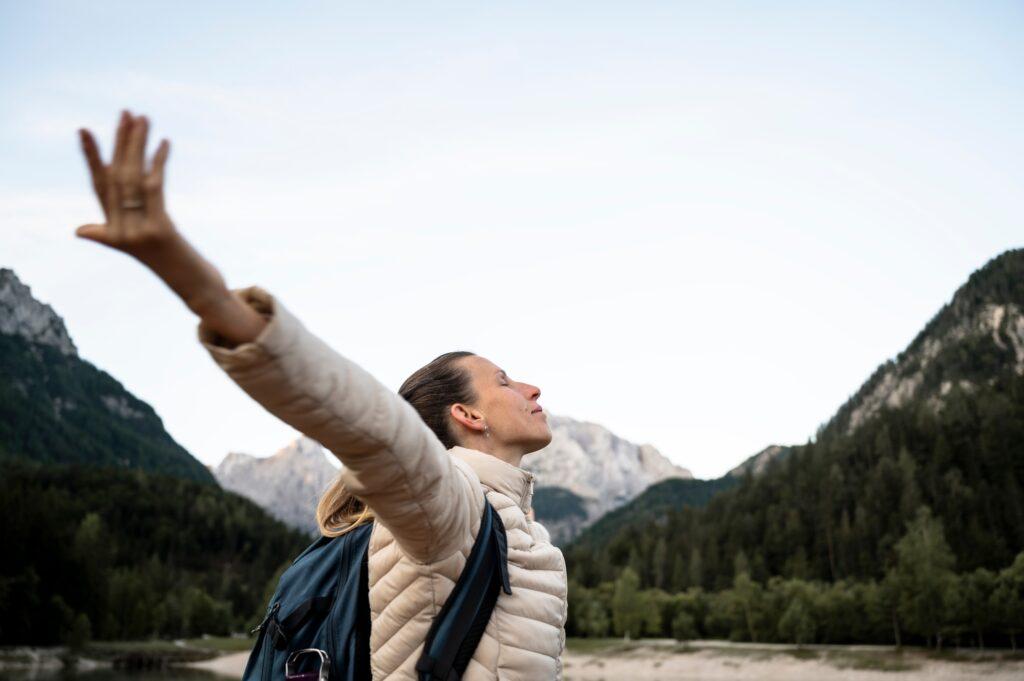 Young woman enjoying her life with arms spread while taking a break during a hike