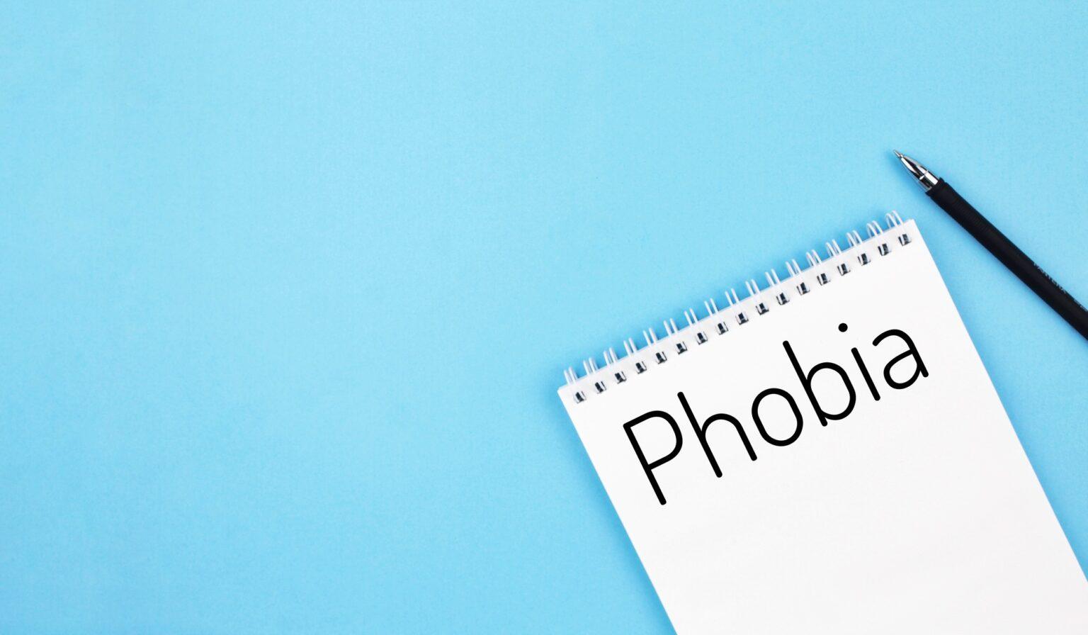 notebook with word phobia on a blue background
