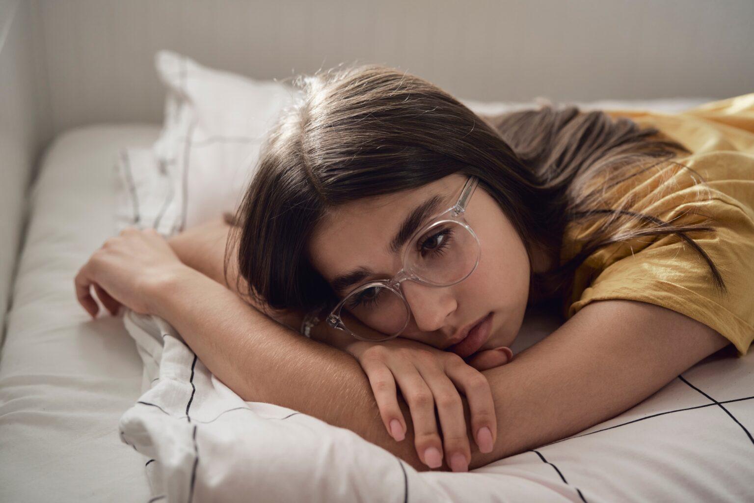 Comprendre l’émetophobie : causes, symptômes et solutions en 2025 Sad caucasian teenage girl lying on bed and looking away with anxiety