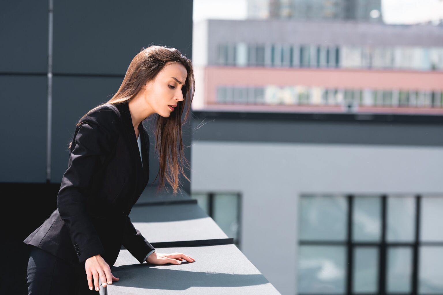 Qu’est-ce que l’acrophobie et comment la surmonter ? young businesswoman, suffering from acrophobia, looking down rooftop