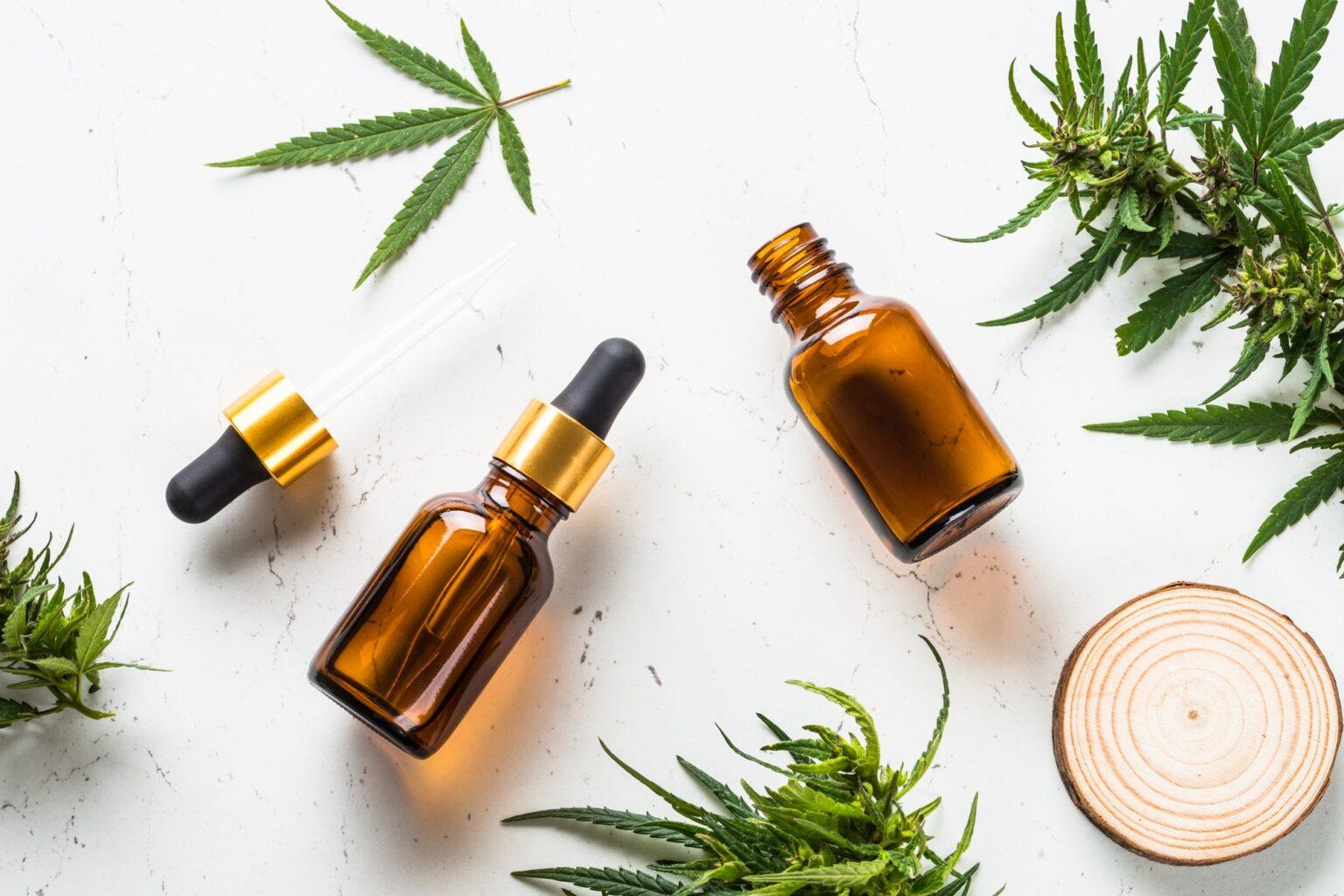 CBD oil and cannabis leaves at white table