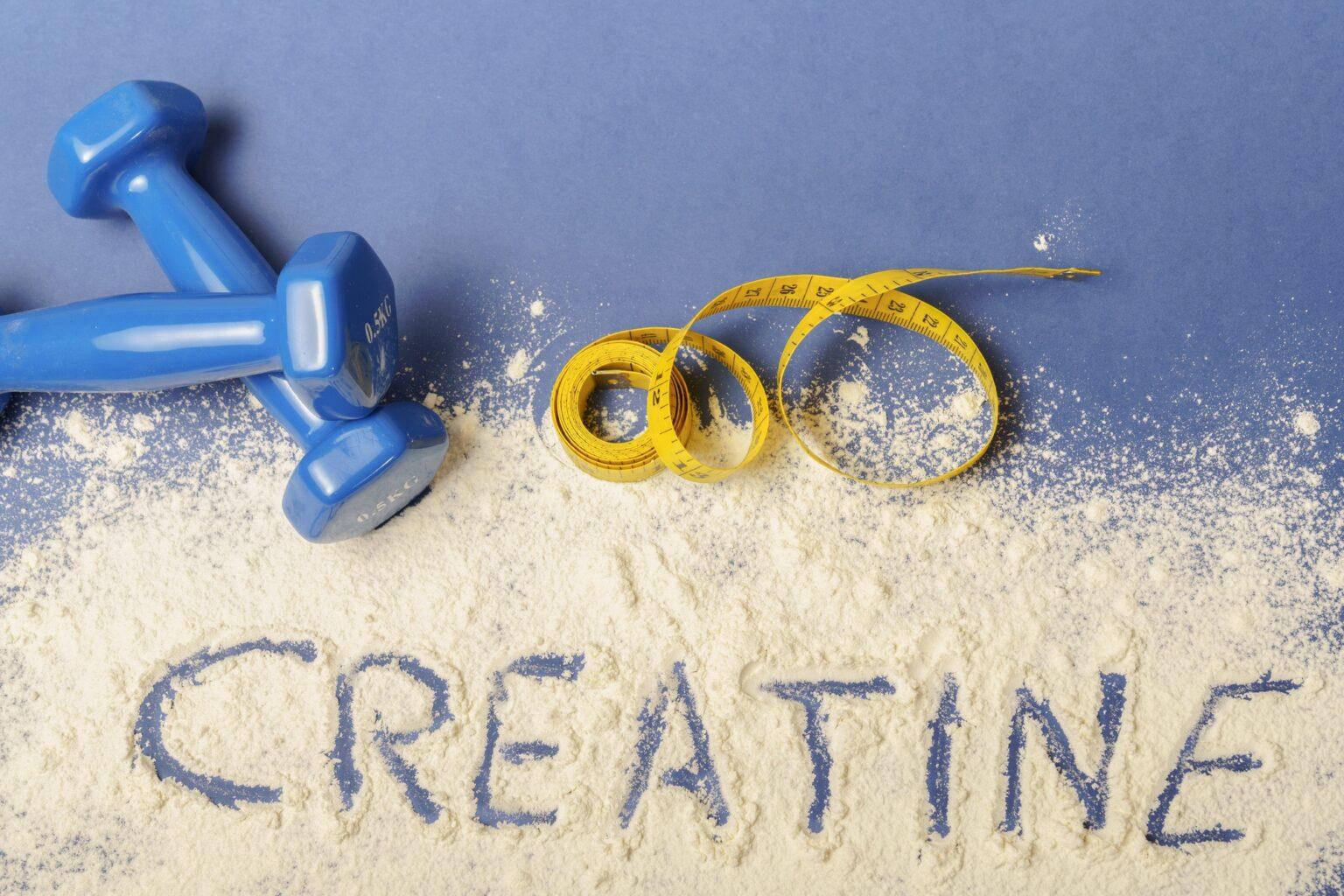 word creatine written on creatine powder on blue background
