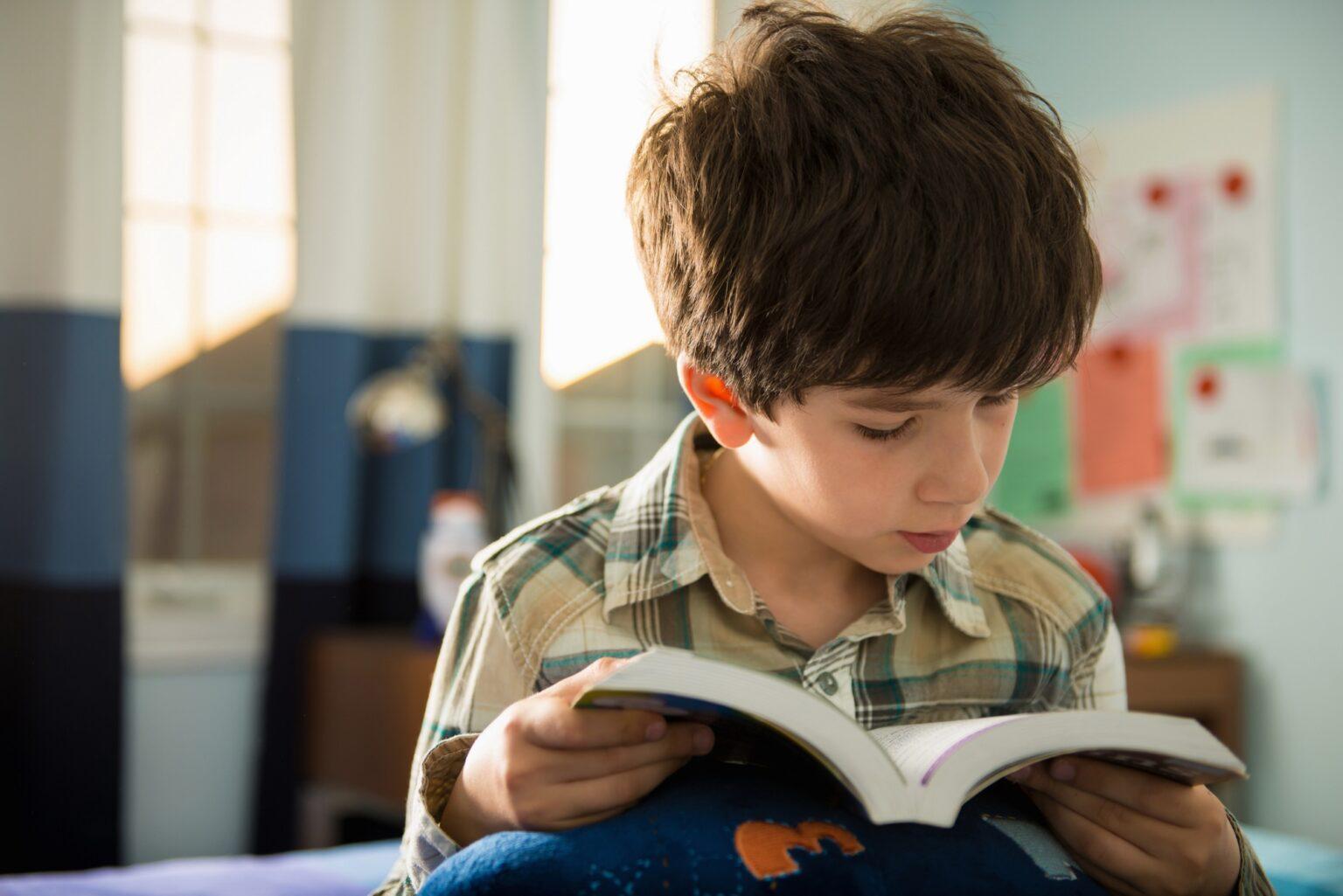 Boy sitting on bed reading book