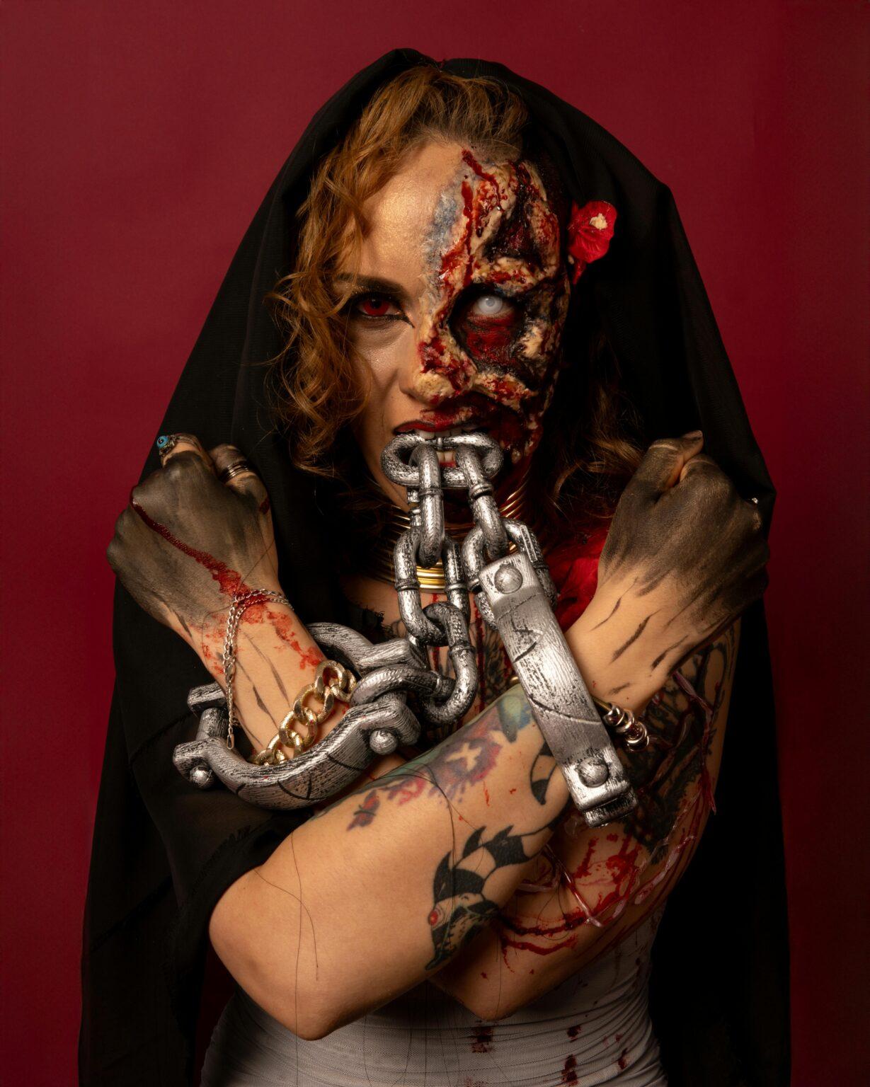Creative horror portrait featuring intense makeup, fake blood, and metal chains.