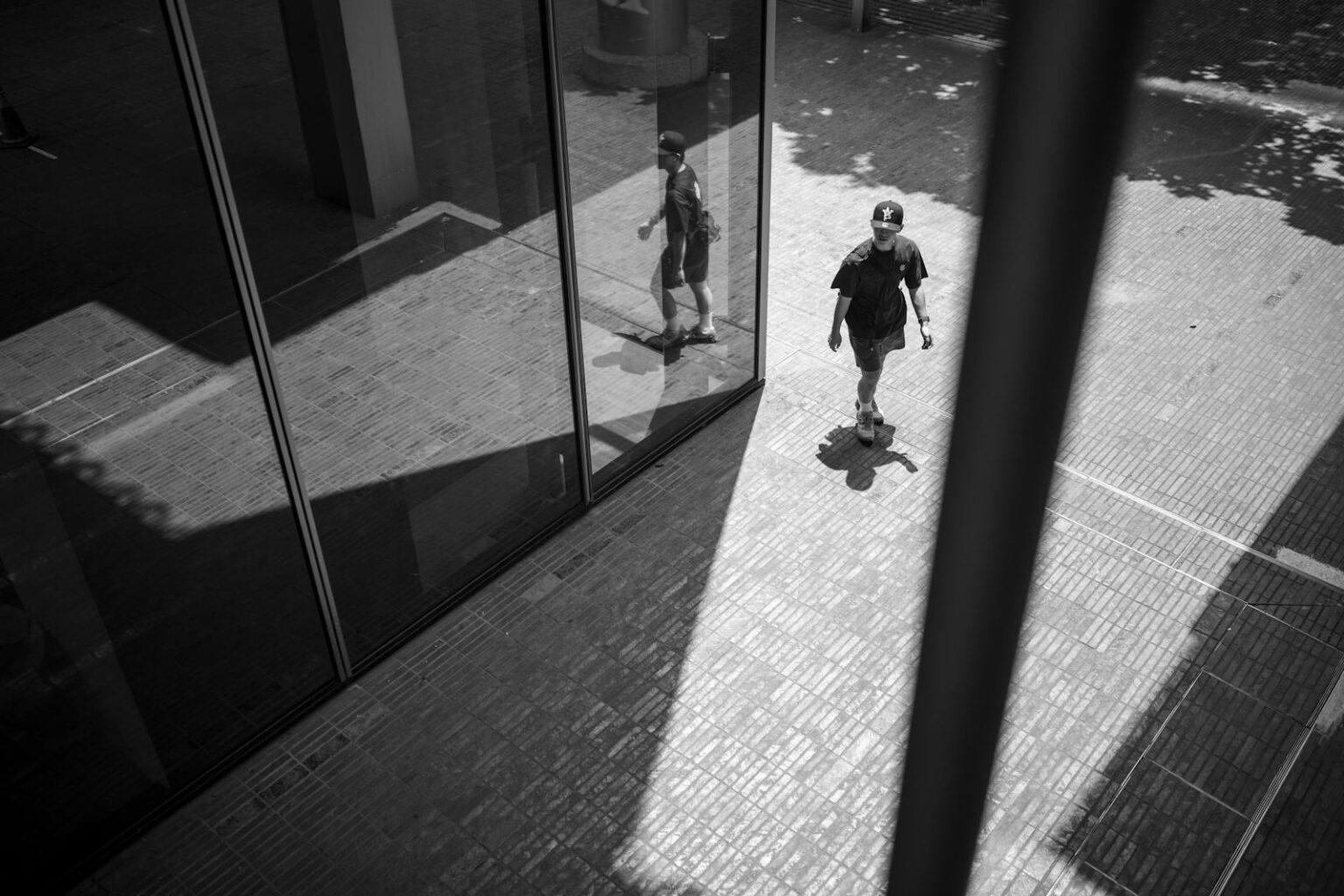 Comment retrouver une libido épanouie : conseils et astuces efficaces A person walks outdoors reflected in a modern glass facade, creating unique shadows.