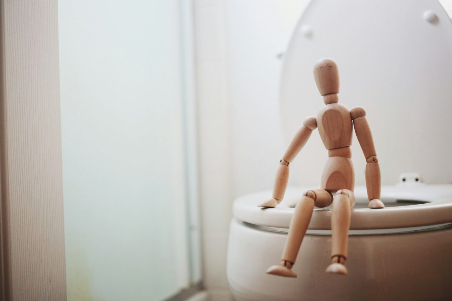Ablutophobie : comprendre la peur irrationnelle de la toilette brown wooden doll on white ceramic toilet bowl