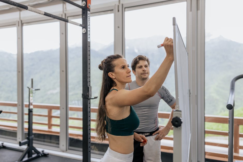 Peut-on s’entraîner à ressentir plus de joie ? Guide complet avec preuves scientifiques Female fitness coach writes on whiteboard as a male athlete watches in a gym.