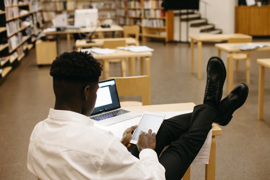 Étudiant travaillant avec concentration dans une bibliothèque universitaire, symbole d'agilité d'apprentissage et de résilience académique