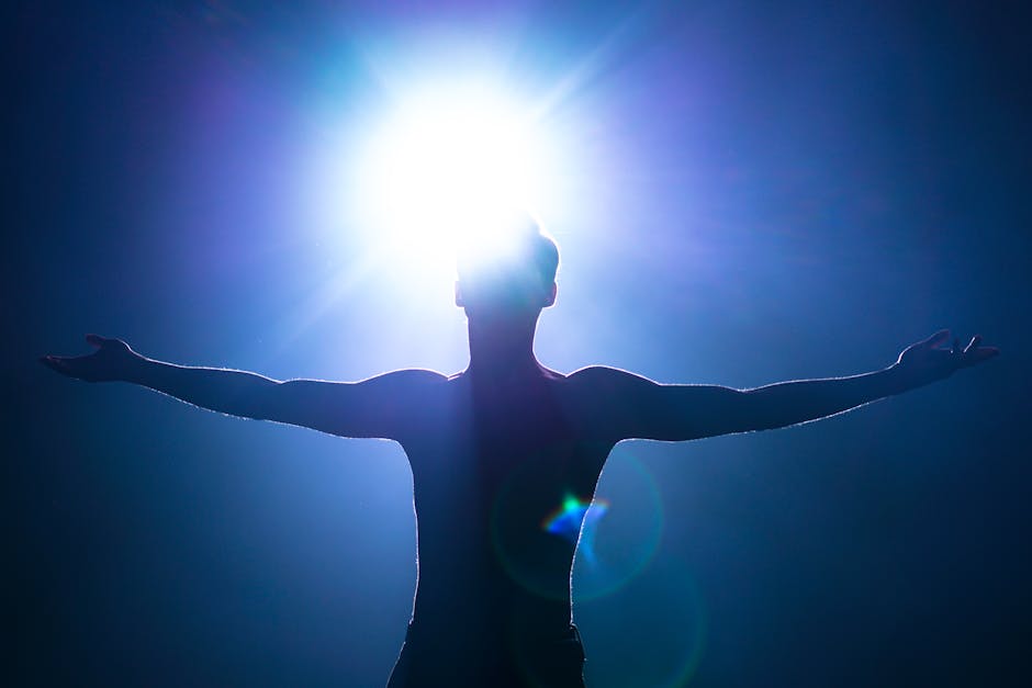 L’émerveillement et la transcendance : États émotionnels positifs pour la santé mentale Silhouette of a man with arms raised, backlit by bright sun, creating an artistic effect.