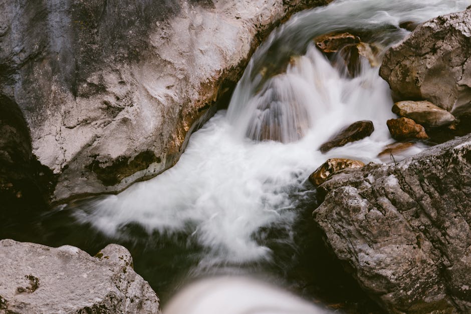 Flow et sens : la connexion profonde A tranquil stream flows over rocks, creating a small waterfall in a natural setting.