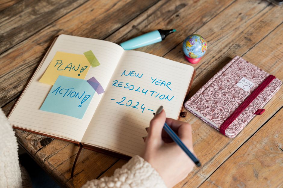 Person writing goals in a notebook with a focused planning mindset