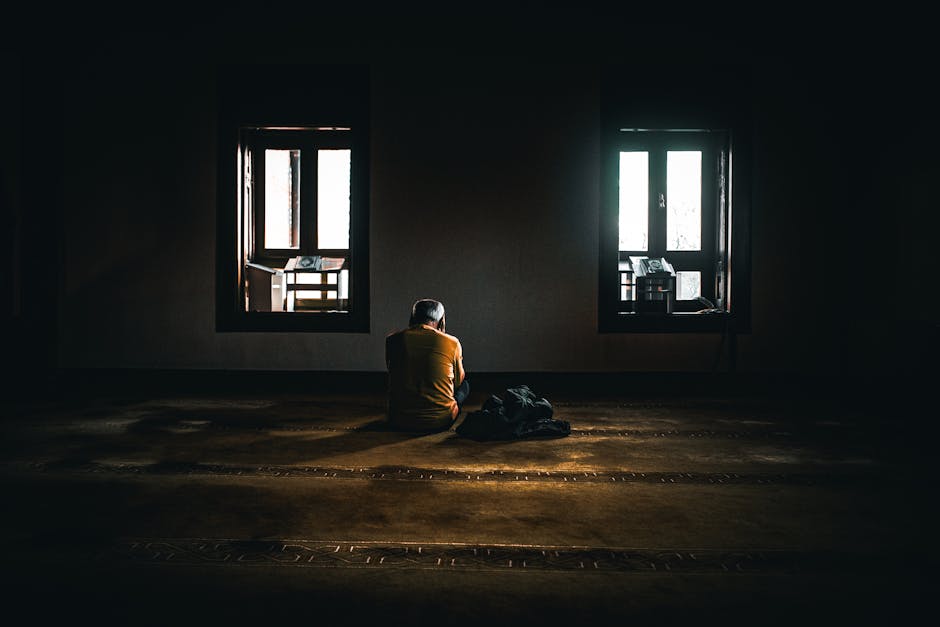 Person reflecting alone by a window, symbolizing search for meaning