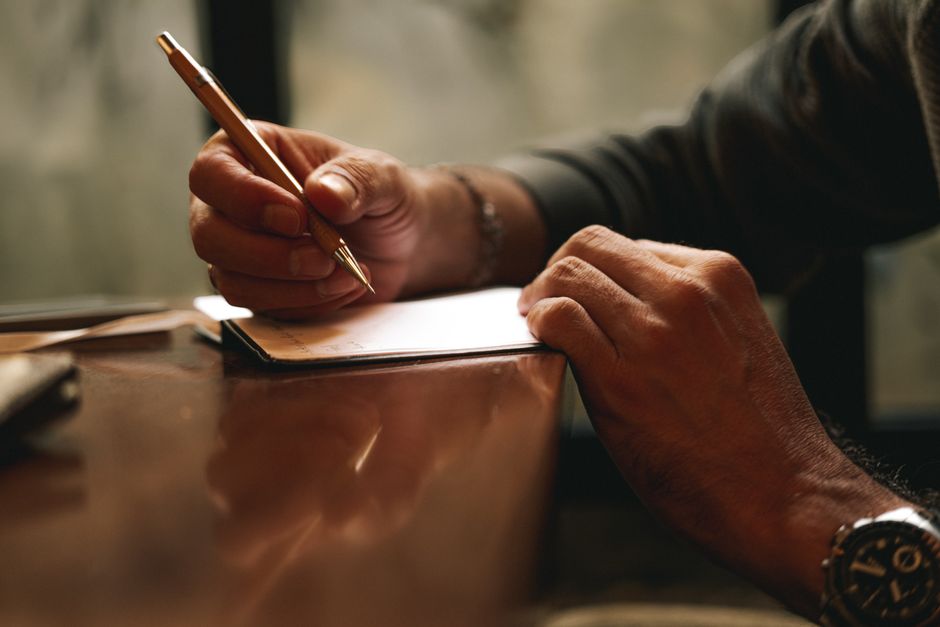 Hands writing a legacy letter in a notebook