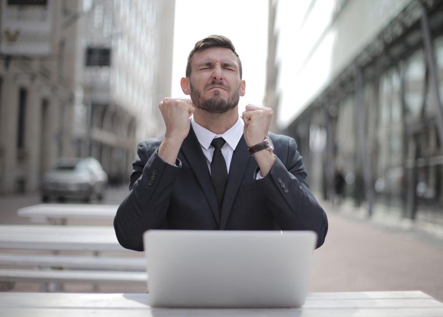 Accomplissement vs épanouissement : la nuance qui change une vie Confident businessman in Budapest celebrates success with a fist pump, reflecting a professional achievement.