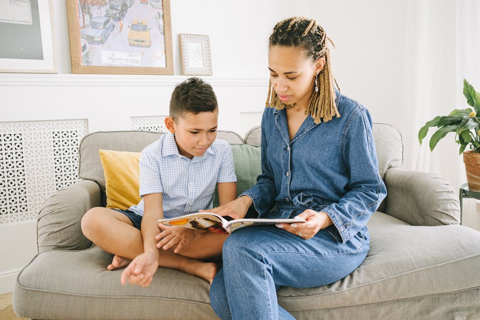 Le récit de vie : raconter son histoire comme source de sens A mother and her son share quality time reading a book together on the couch in a cozy room.