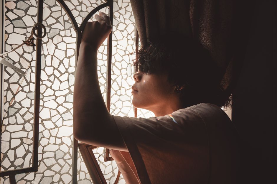 Person grieving alone by a window