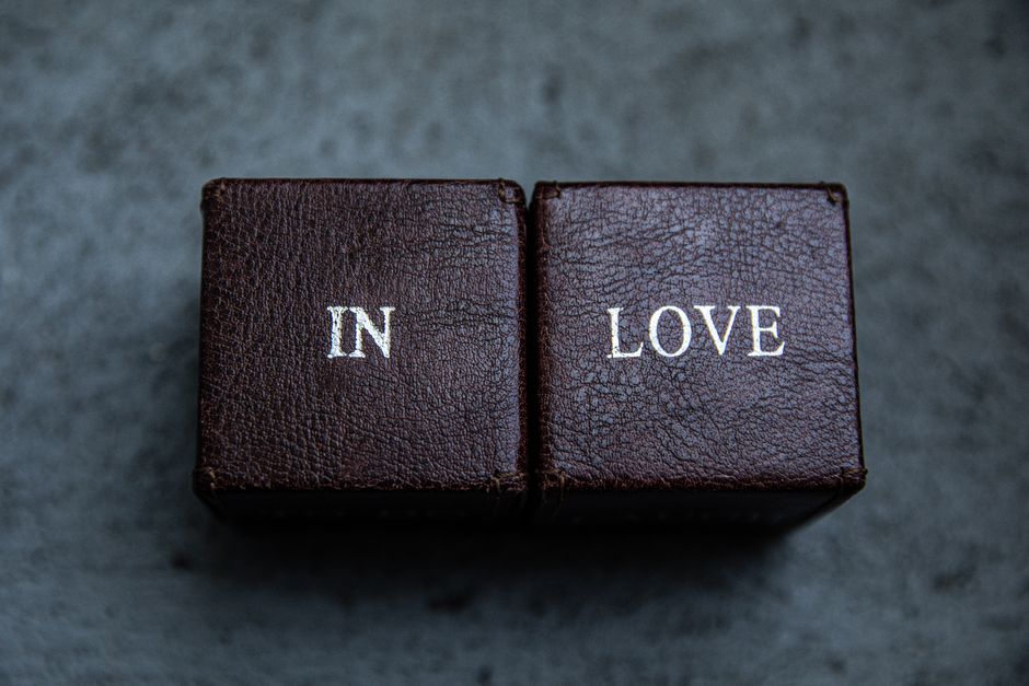 Mentorat et sentiment de but : comment une relation influe sur le sens d’une vie Close-up of two brown leather blocks with the text "In Love" on a dark textured background.