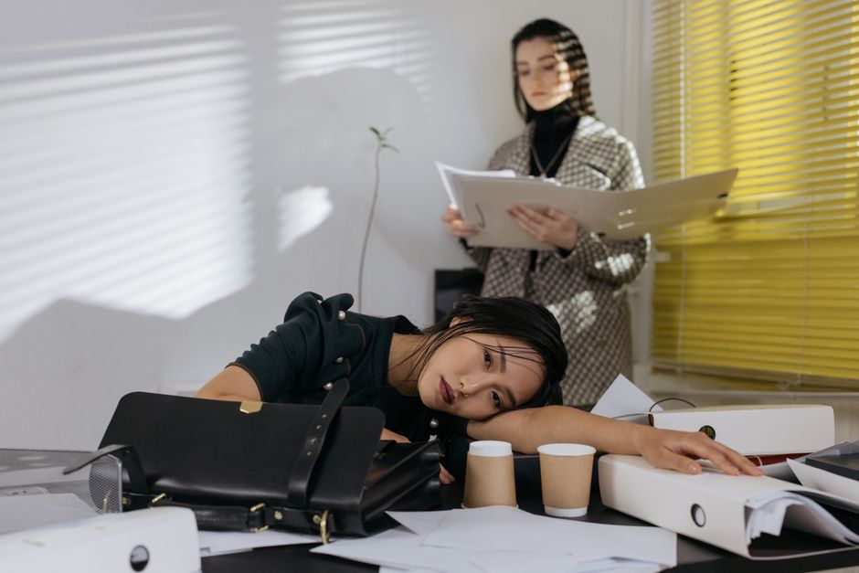 Professional working at desk with laptop and documents, feeling accomplished but tired