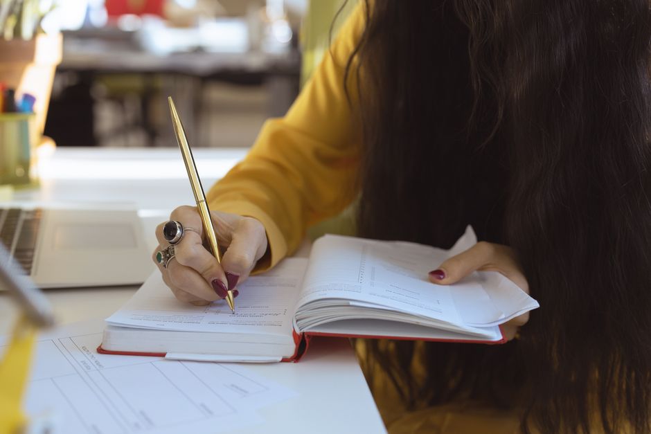 Person journaling with notebook and pen at a desk