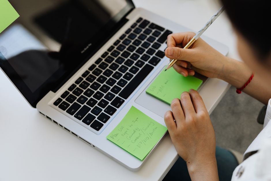 Professional working on task organization with notes and laptop