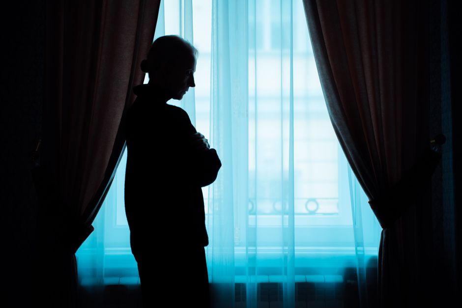 Person sitting alone by a window in reflective light