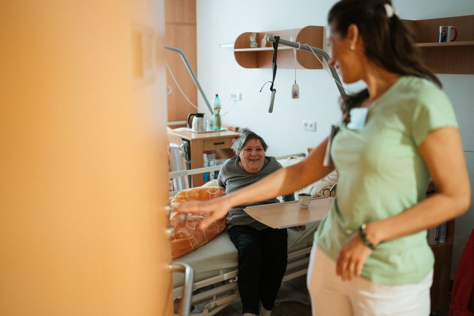A caregiver interacts warmly with an elderly patient in a retirement home's cozy setting.