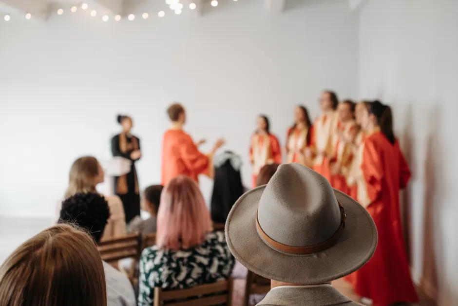 A choir in red robes performs in a church with attentive parishioners listening intently.