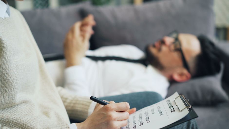 Psychothérapie de l’anxiété : choisir entre individuel, groupe et numérique A client discusses issues during a therapy session with a therapist taking notes, indoors.