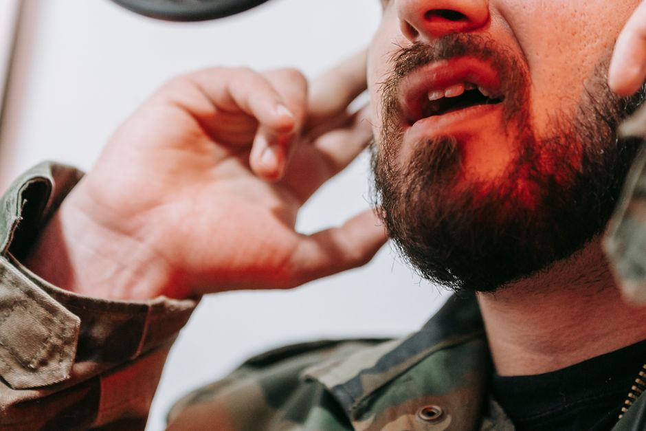 Dyskinésie tardive : comprendre le corps, le lien social et les proches A close-up view of a bearded man talking with hands near his face.