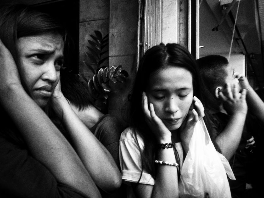 A diverse group of adults covers their ears in distress, illustrating overwhelming sound or noise.