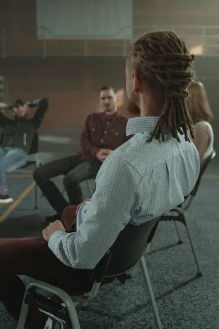 A diverse group of adults engaging in a support therapy session in an indoor setting.