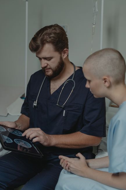 A doctor with a stethoscope discusses MRI results with a patient using a digital tablet.