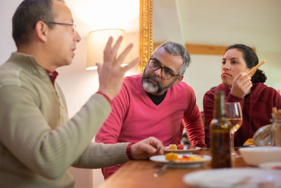 Codépendance : quand aider l’autre finit par vous épuiser A family enjoying a casual meal and engaging conversation in a cozy indoor setting in Portugal.